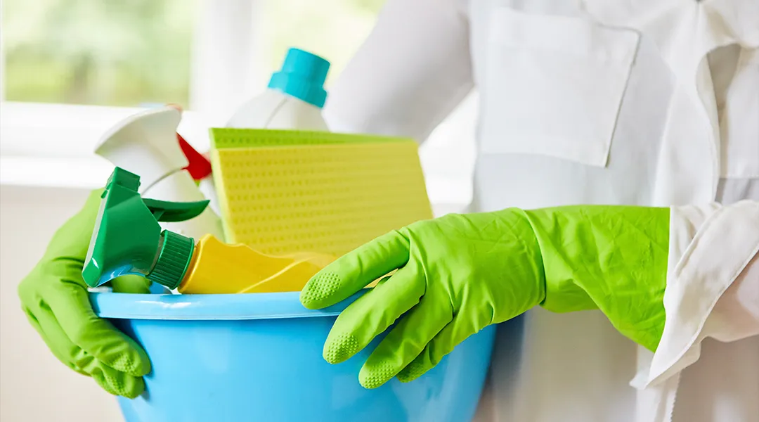 Person holding bucket with cleaning supplies for spring cleaning.